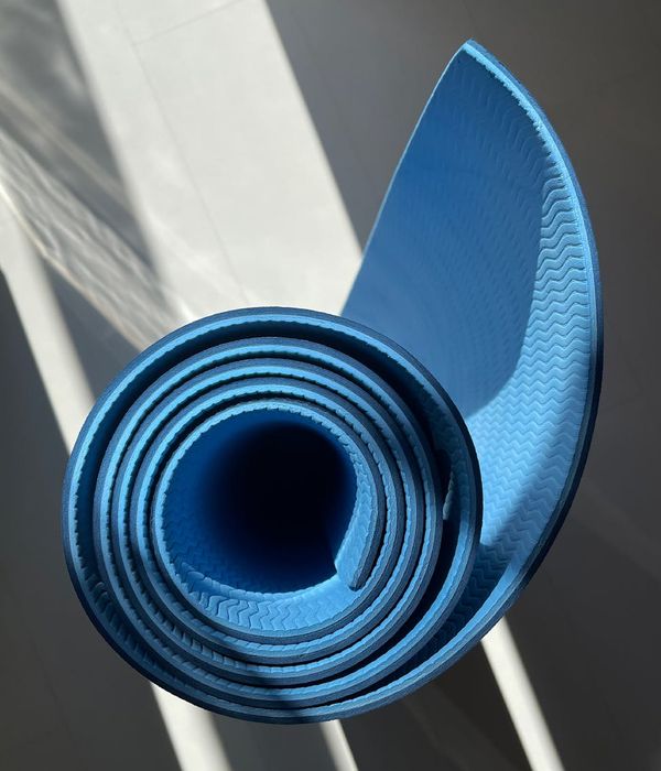 A minimalist yoga mat on a clean wooden floor.